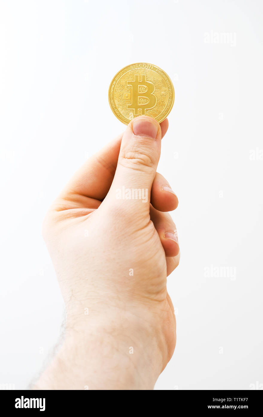 Mann hält physische Version von golden Bitcoin auf weißem Hintergrund. Stockfoto