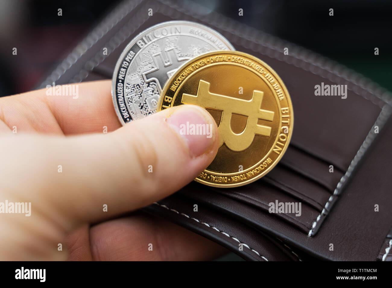 Mann hält physische Version von goldenen und silbernen Bitcoins. Stockfoto