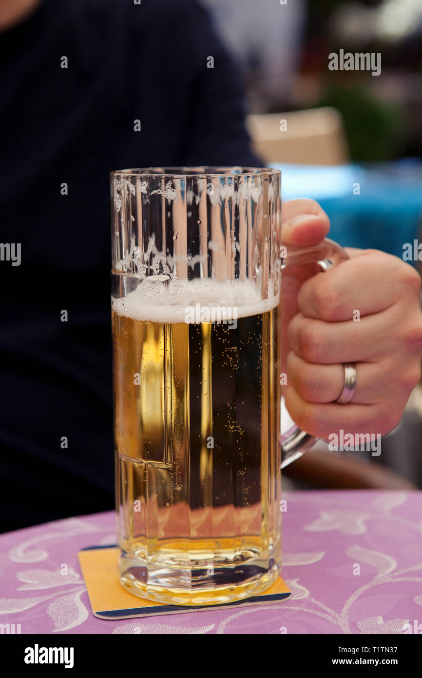 Mann hält Glas humpen Bier auf einen Tisch in einem Street Cafe Stockfoto
