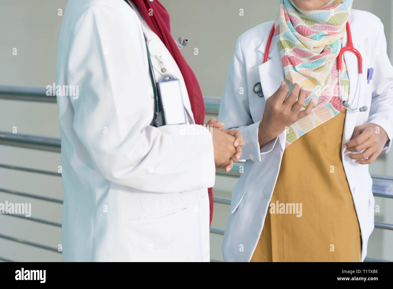 Schwere zwei Weibliche asiatische hijab Arzt besprechen und Studieren über Dokument des Patienten im Krankenhaus Zimmer Stockfoto