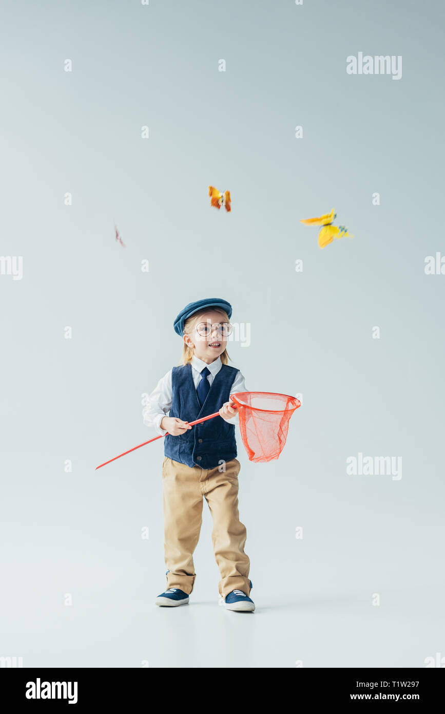 Cute kid im Retro-look Weste und Kappe Schmetterlinge fangen mit Butterfly net Stockfoto