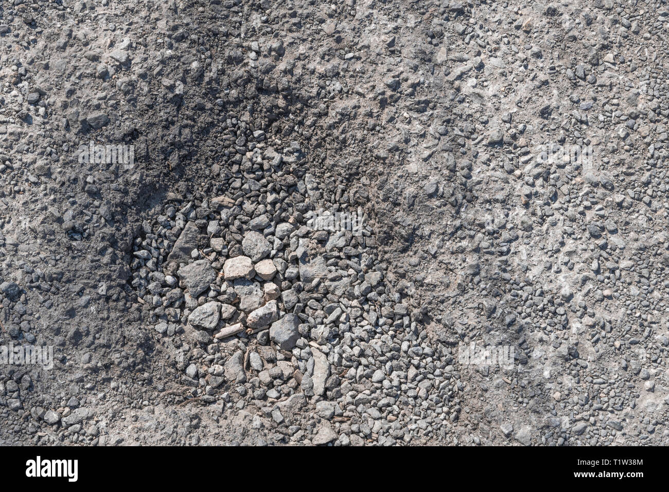 Schlagloch im hardcore Kies Land verfolgen. Metapher für schlecht gewartete Straßen, holperig, rough Road, schlechte Straßen, Loch in der Straße. Stockfoto