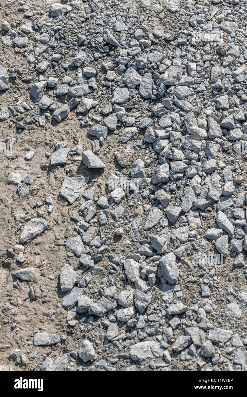 Kleine Schottersteine/Hard-core-kies Oberfläche eines Landes verfolgen. Metapher für 'fallen auf steinigem Boden', schlechte Qualität, rauhe Straße Konzept, kleine Steine Stockfoto