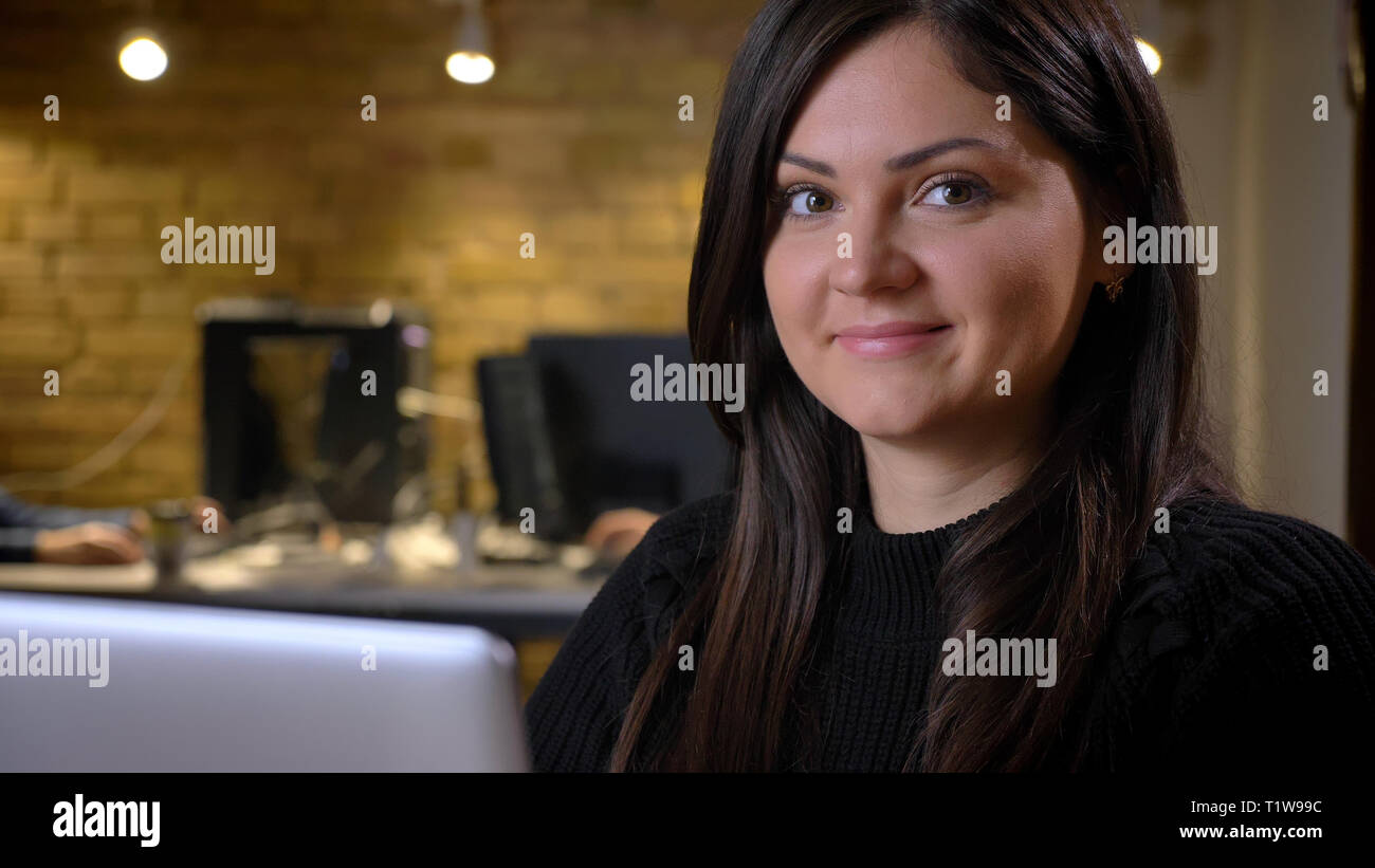 Close-up Portrait von im mittleren Alter übergewichtig Geschäftsfrau am Laptop und lächelnd in die Kamera auf Büro Hintergrund. Stockfoto