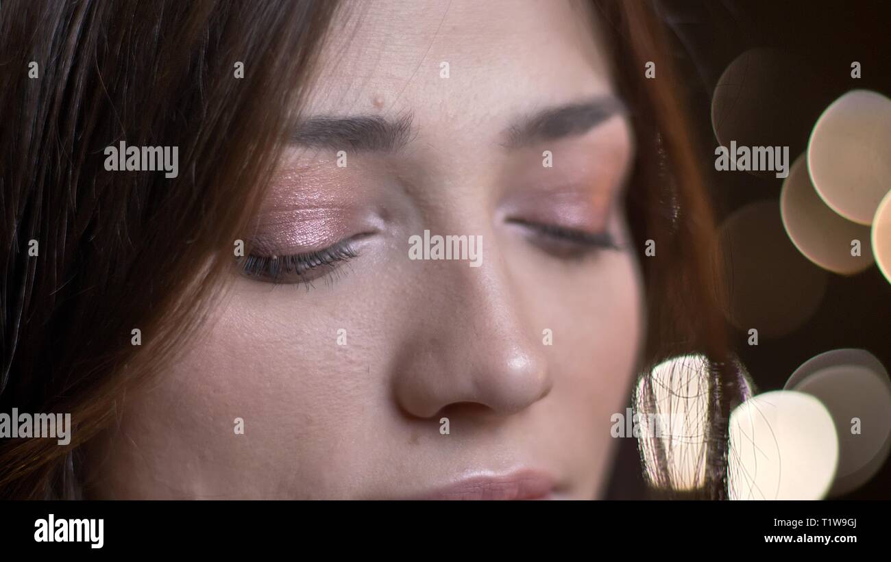Close-up Eye - Porträt der schönen kaukasischen brunette Mädchen gerade nach unten verschwommen Lichter Hintergrund. Stockfoto