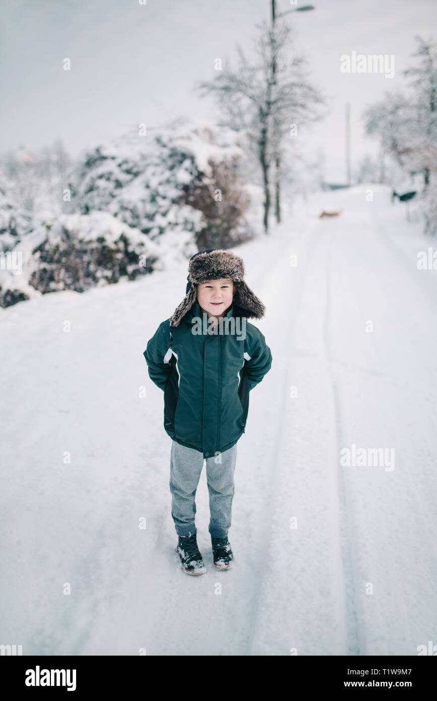 Junge mit lustigen Hut stehend im Schnee Stockfoto