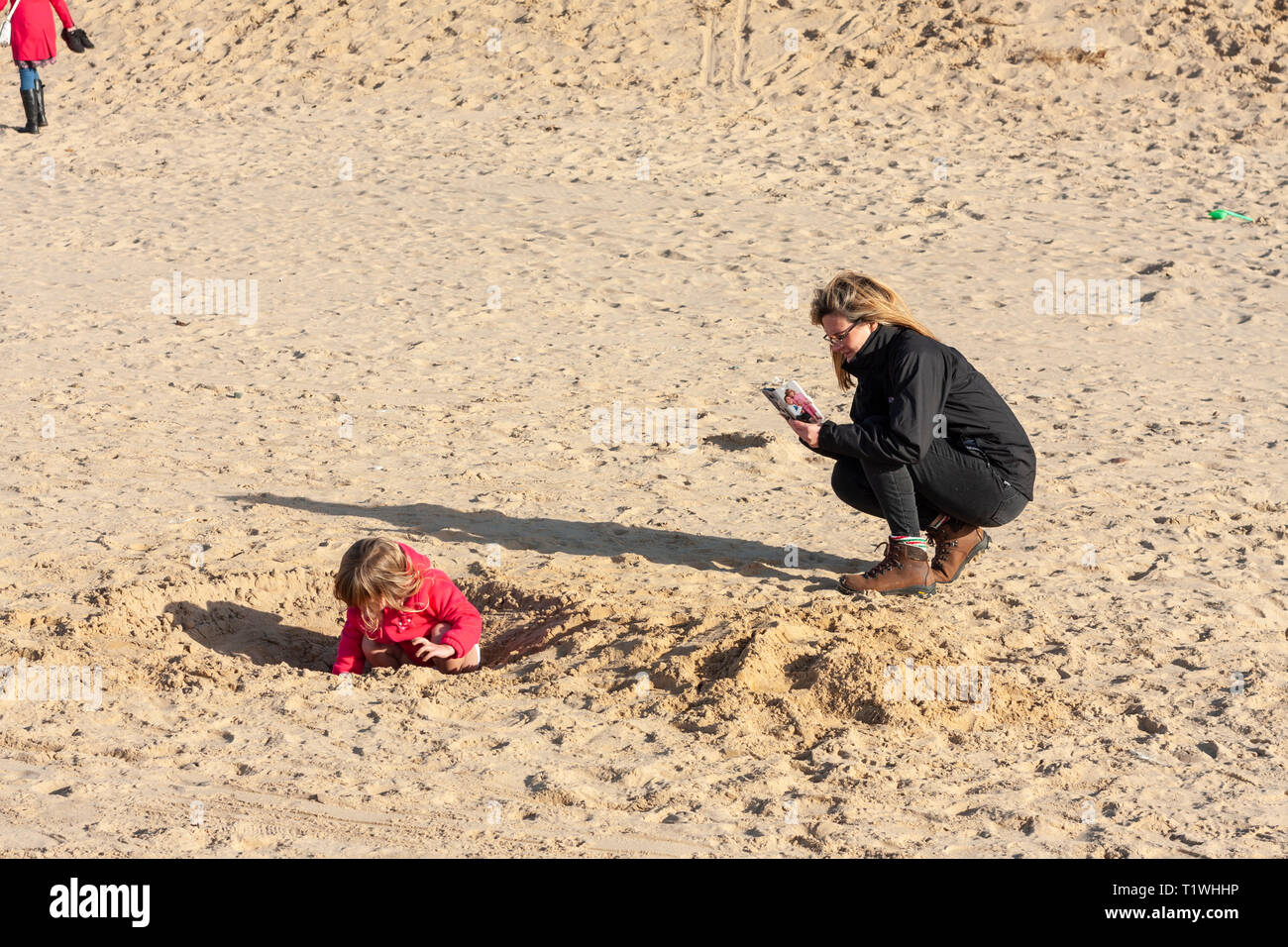 Ein Erwachsener ein Bild von einem jungen Mädchen spielen im Sand auf Formby Strand, Merseyside, UK Stockfoto