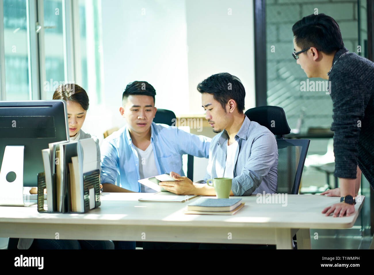 Vier jungen asiatischen Führungskräfte gemeinsam diskutieren business plan im Amt. Stockfoto