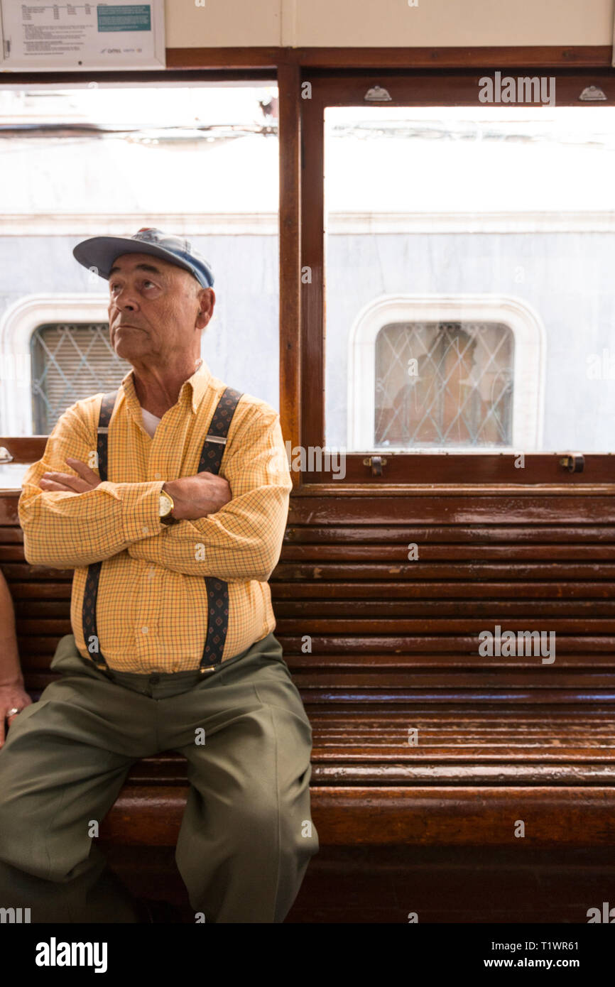 Ein älterer älterer Portugiese reiten fahren Sie mit der Straßenbahn zum Barrio Alto, Lissabon, Portugal. Er trägt Hosenträger. Stockfoto