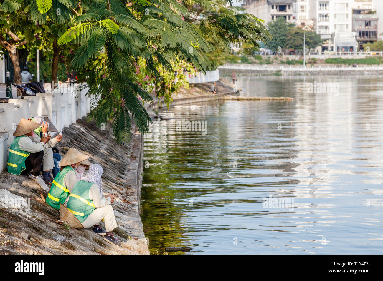 Vietnamesische Arbeitnehmer ruht in der Nähe von Quan Tay Ho oder Westlake District in Hanoi. Bank von See Tay mit residentian Gebäude und Restaurants. Vietnam. Stockfoto