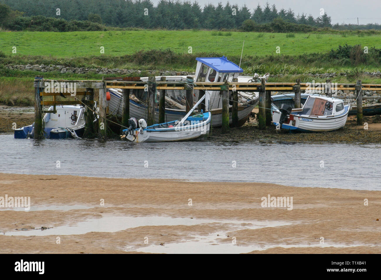 Kleine Boote neben einem Pier bei Ebbe in Irland auf dem culdaff River auf der Halbinsel Inishowen, County Donegal. Stockfoto