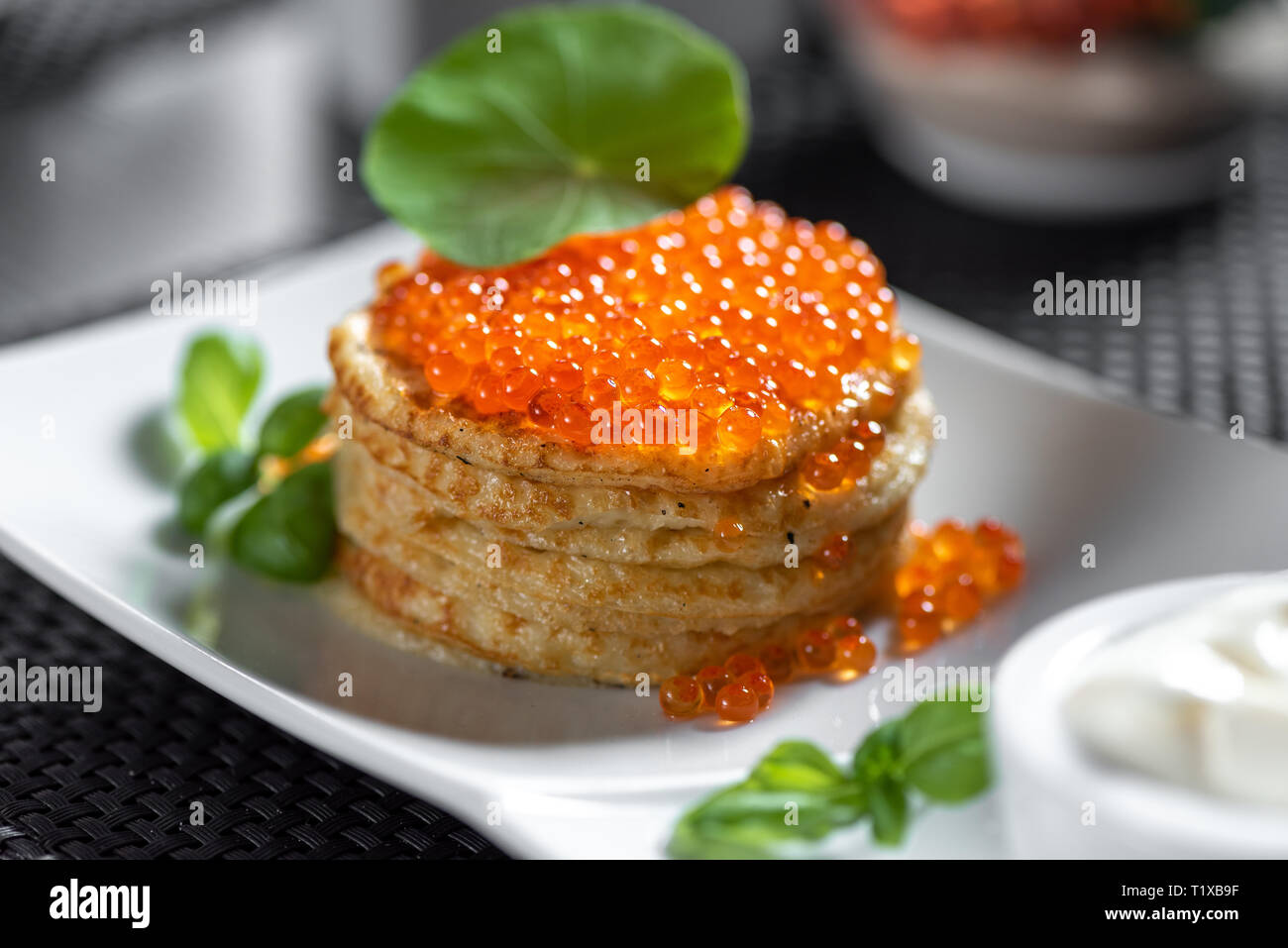Pfannkuchen mit Kaviar im "russischen Stils" auf dunklem Hintergrund. Stockfoto