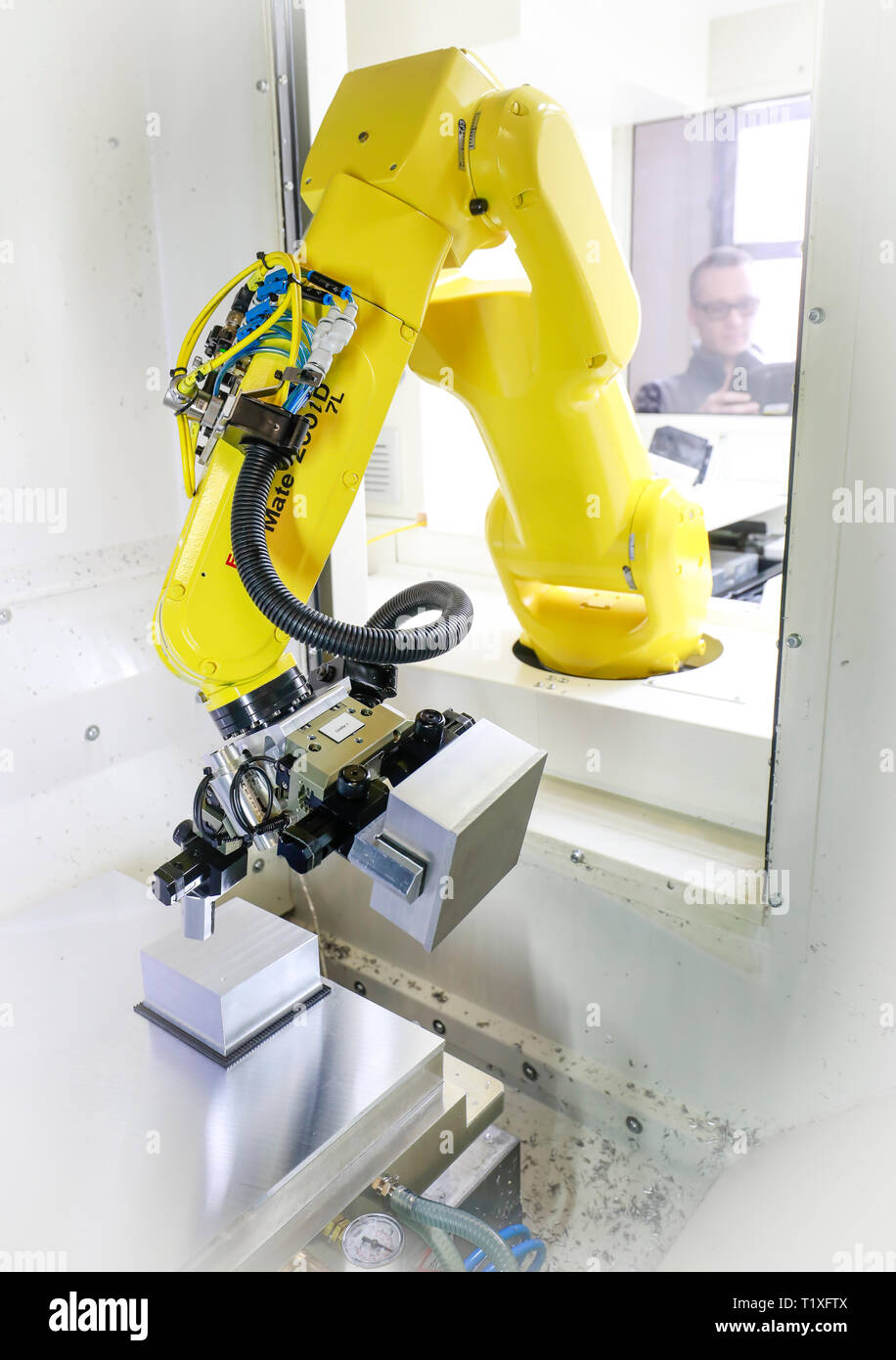 Bochum, Nordrhein-Westfalen, Deutschland - Roboterarm stattet eine CNC-Fräsmaschine mit Werkstücke hier auf Stromboli Elektro- und Feinwerktechnik auf der Stockfoto