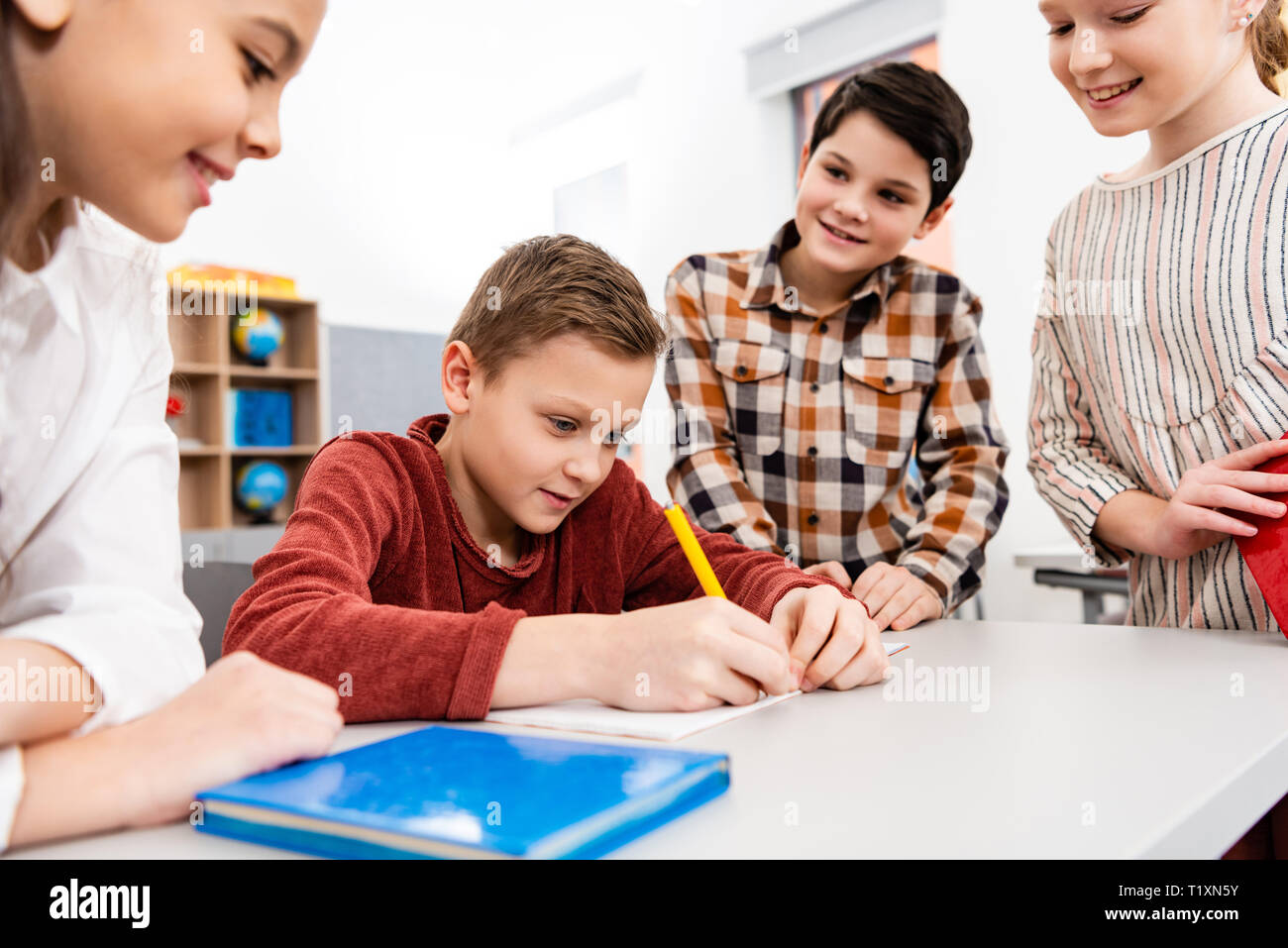 Lächelnd Schülerinnen und Schüler mit Notebooks und Bücher Diskutieren im Klassenzimmer Stockfoto
