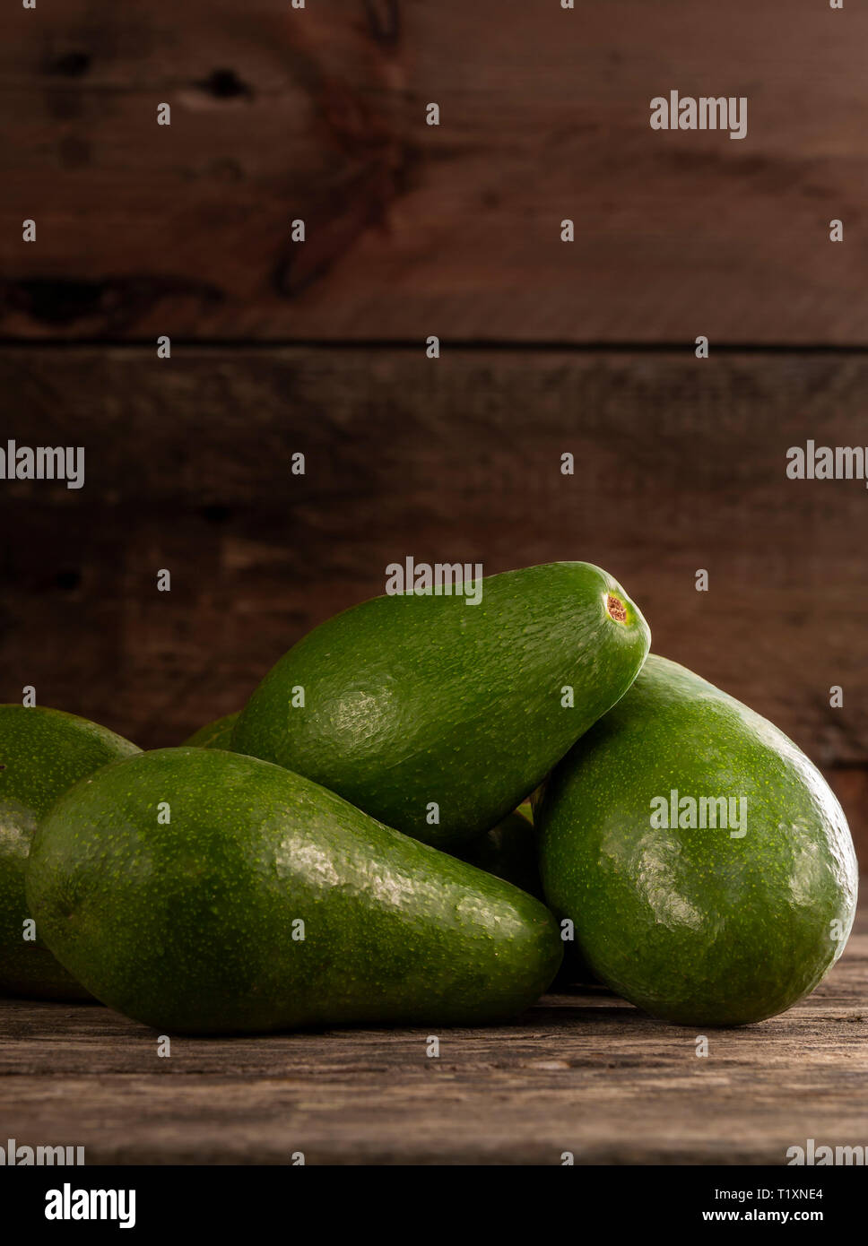 Stapel der ungeschälte helle grüne Avocados auf Holz rustikale Tabelle Stockfoto