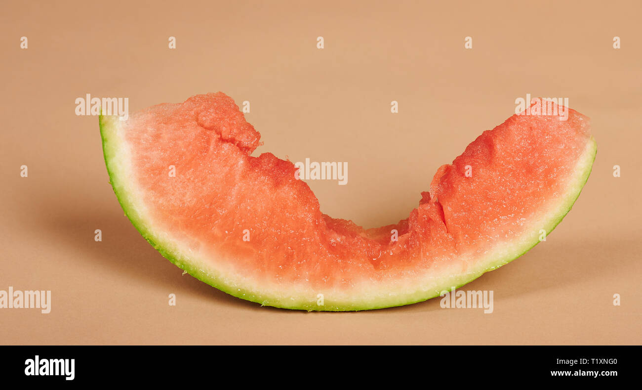 Die Hälfte gegessen Wassermelone Stück auf braunem Hintergrund isoliert Stockfoto