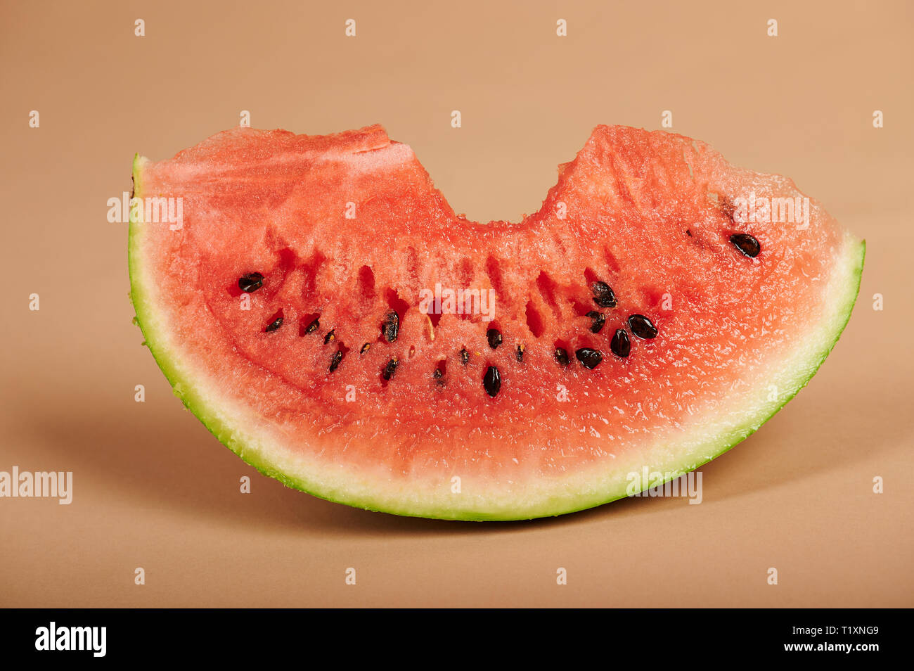 Frische Wassermelone Stück mit Biss auf Braun studio Hintergrund Stockfoto