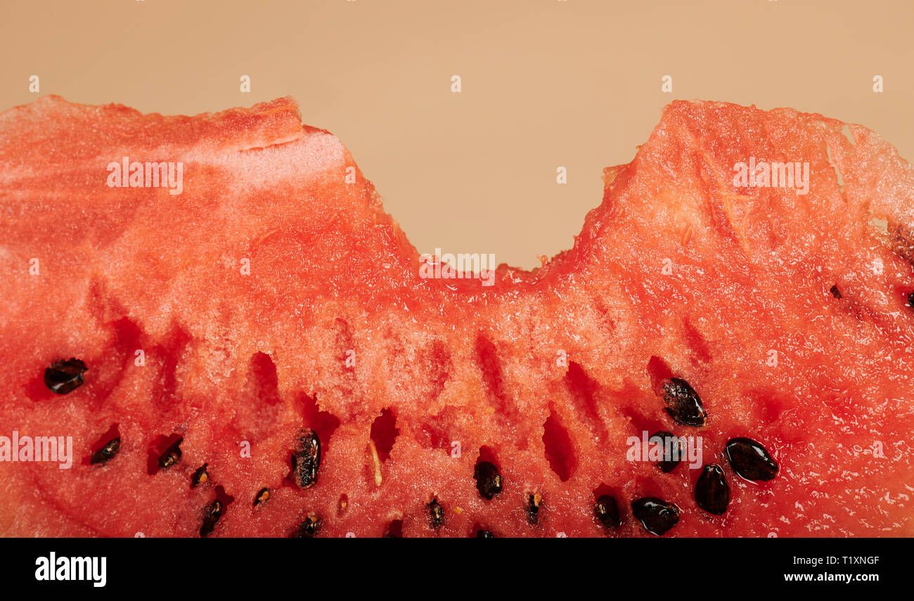 Ein Biss auf Wassermelone Stück makro Blick auf braunem Hintergrund Stockfoto