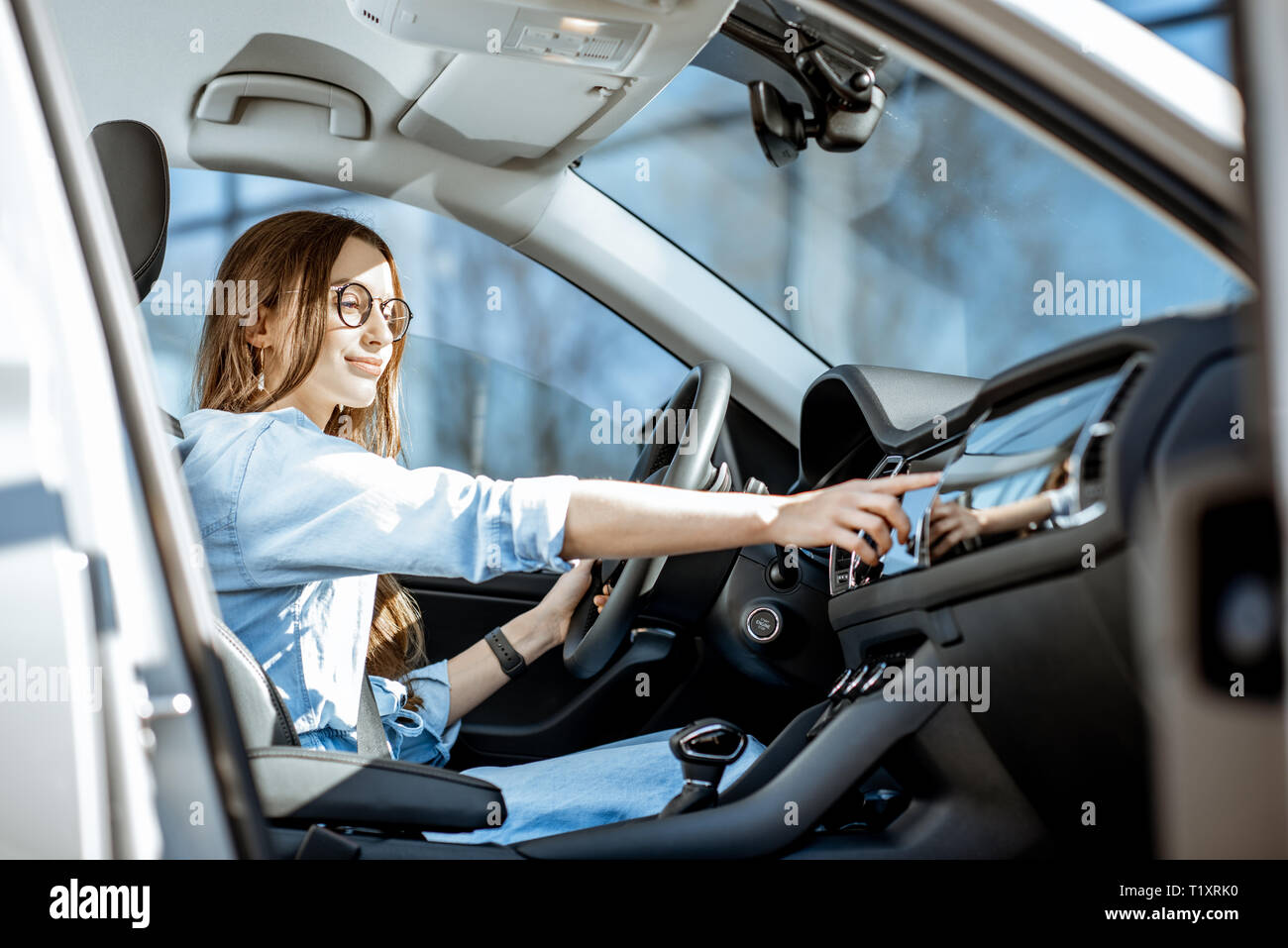 Junge Frau berühren Auto überwachen, während in der modernen Autos in der Stadt sitzen Stockfoto
