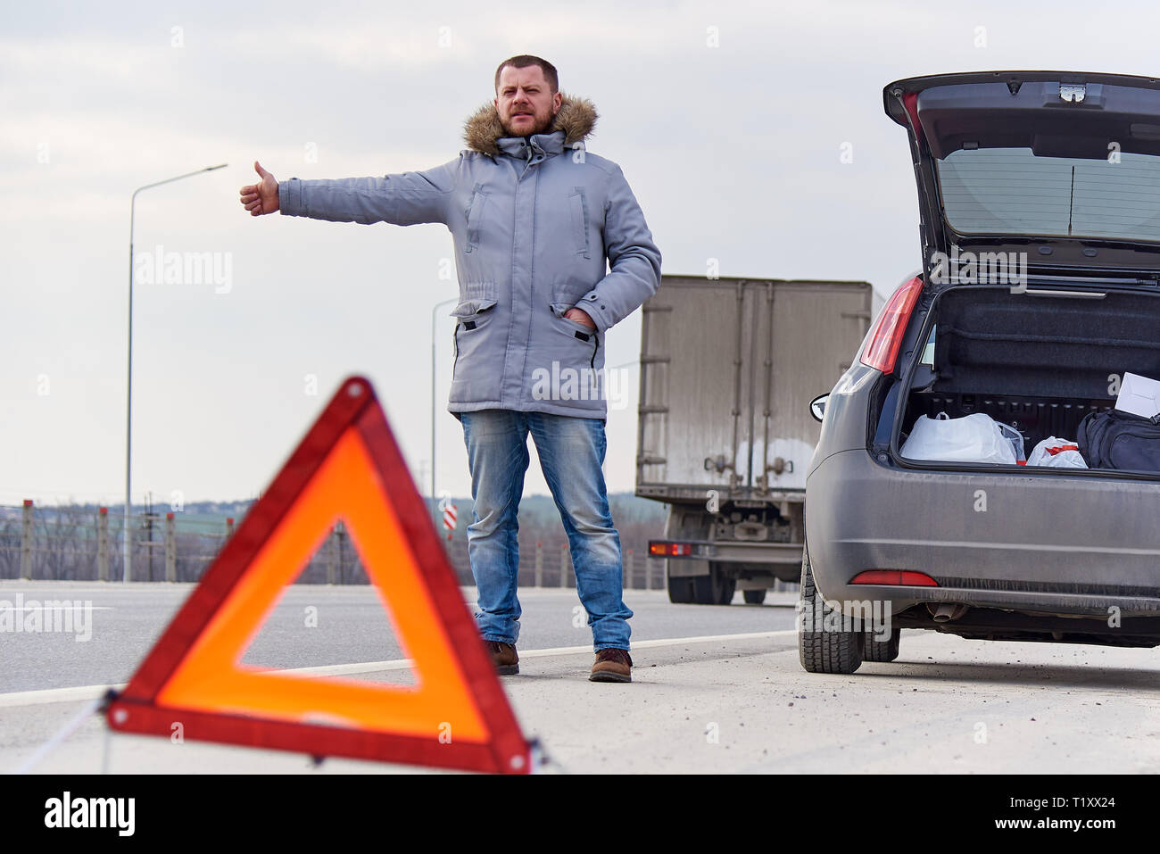 Junger Mann per Anhalter auf der Straße Stockfoto