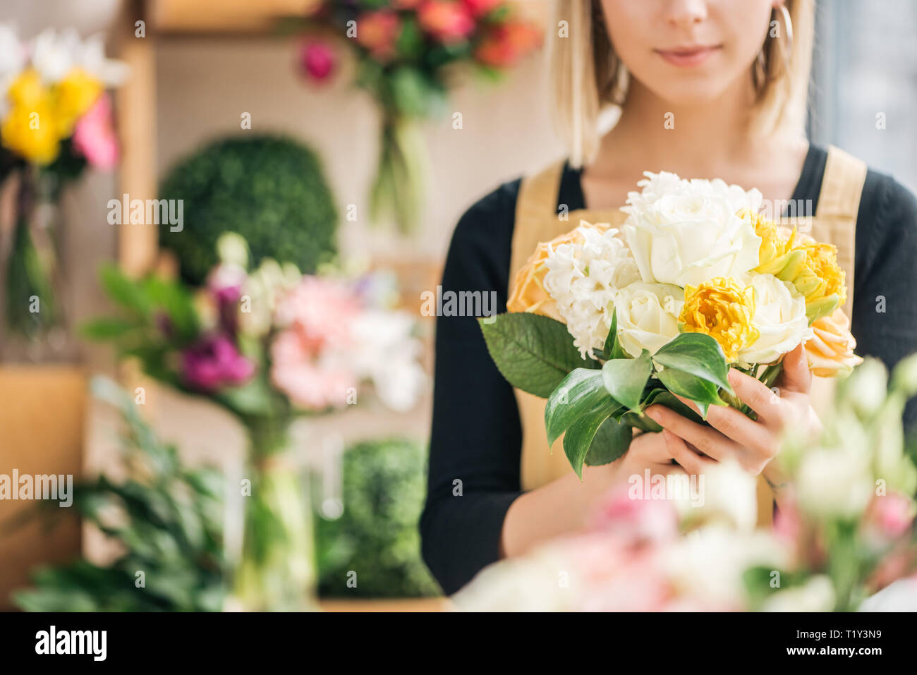 7/8-Ansicht der Blumenhändler in Schürze holding Blumenstrauß in Flower Shop Stockfoto