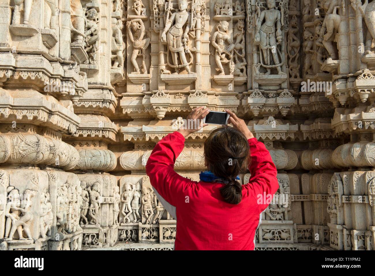 Indien, Rajasthan, RANAKPUR, 2013-12-23: Frau Fotos mit einem Smart Phone von Skulpturen in Ranakpur Tempel Stockfoto