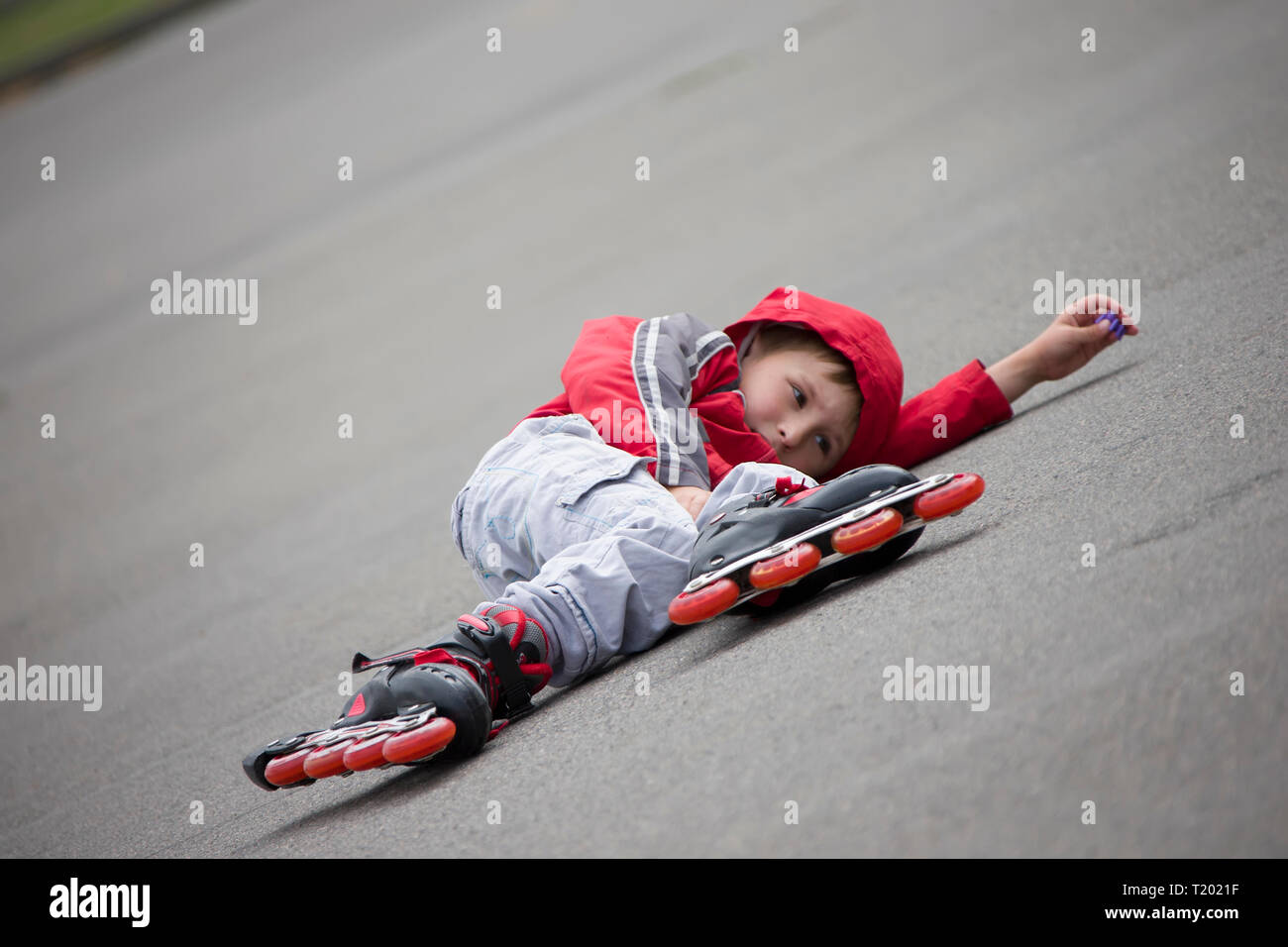 Der Junge im Rollschuhe liegen auf dem Bürgersteig. Das Kind in Rollschuhen fiel Stockfoto