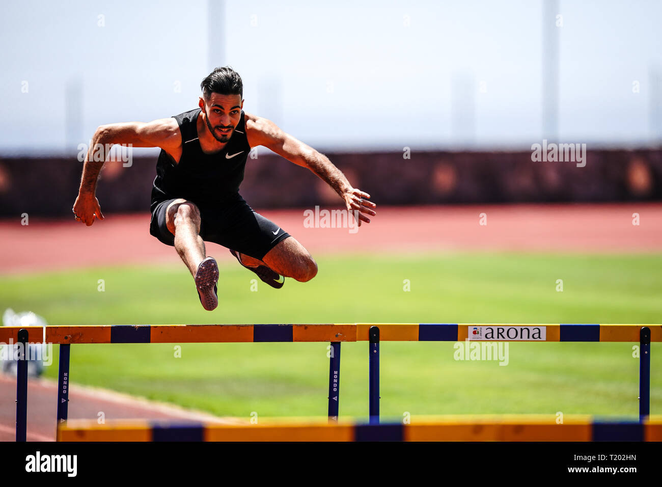 Teneriffa, Spanien - 21. März 2019: Ein Sportler springt über eine Hürde beim Üben auf eine Laufstrecke Stockfoto