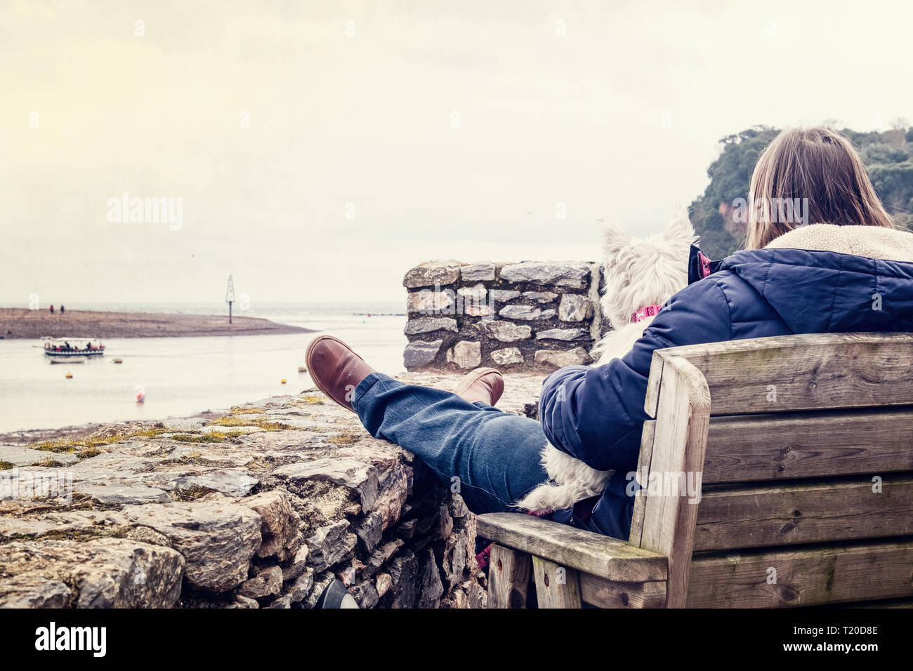 Eine Frau und ein Scottie dog beobachten Die pedestrean Fähre in Shaldon, Devon. Februar 2019 Stockfoto