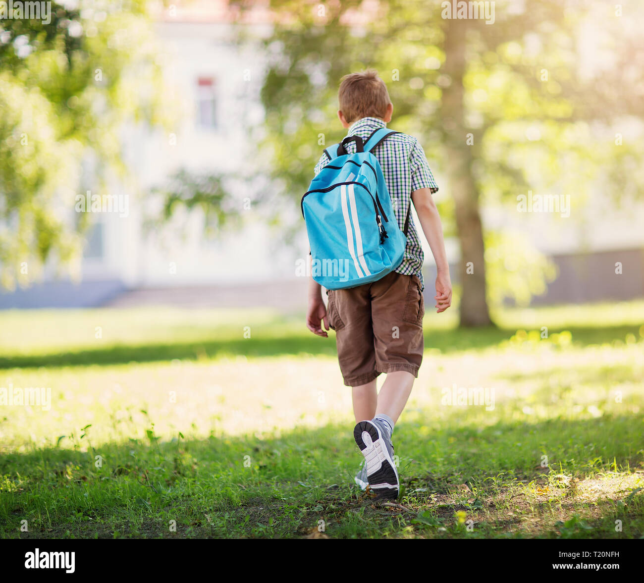 Junge mit Rucksack infront von einem Schulgebäude Stockfoto