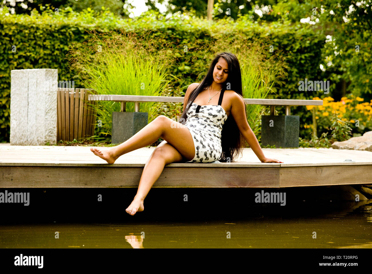 Eine junge Frau sitzt barfuss durch einen Teich. Stockfoto