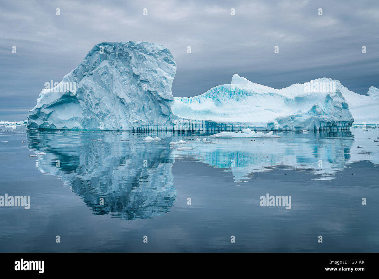 Ein erstaunlicher Eisberg auf dem Eisgraveyard in der Antarktis, der in einem Tierkreis eine schöne Reflexion an der Wasseroberfläche hervorruft Stockfoto