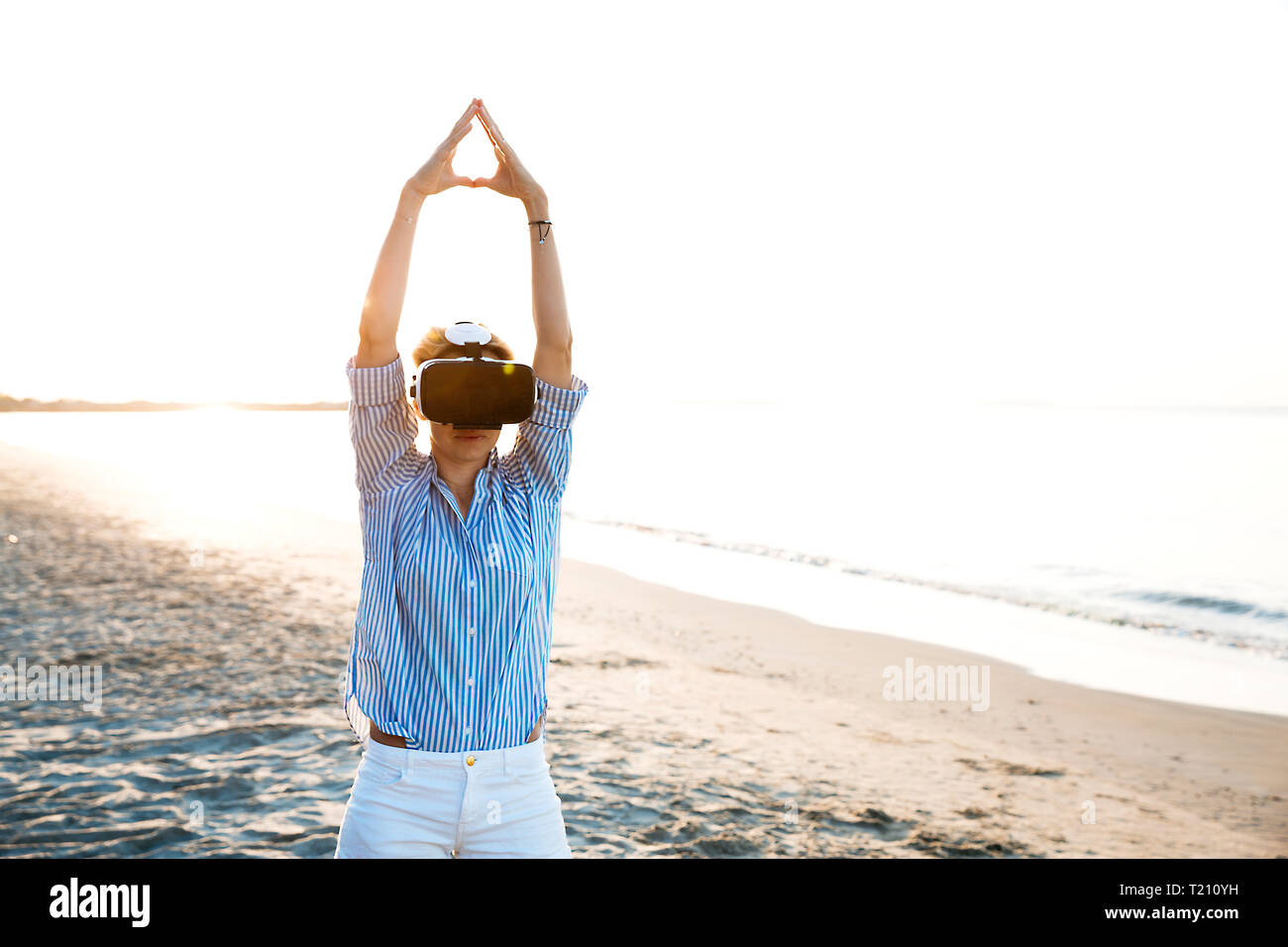Blonde Frau tun Art von Yoga Übungen auf einem Strand in Thailand mit 3D Virtual Reality goggles Stockfoto