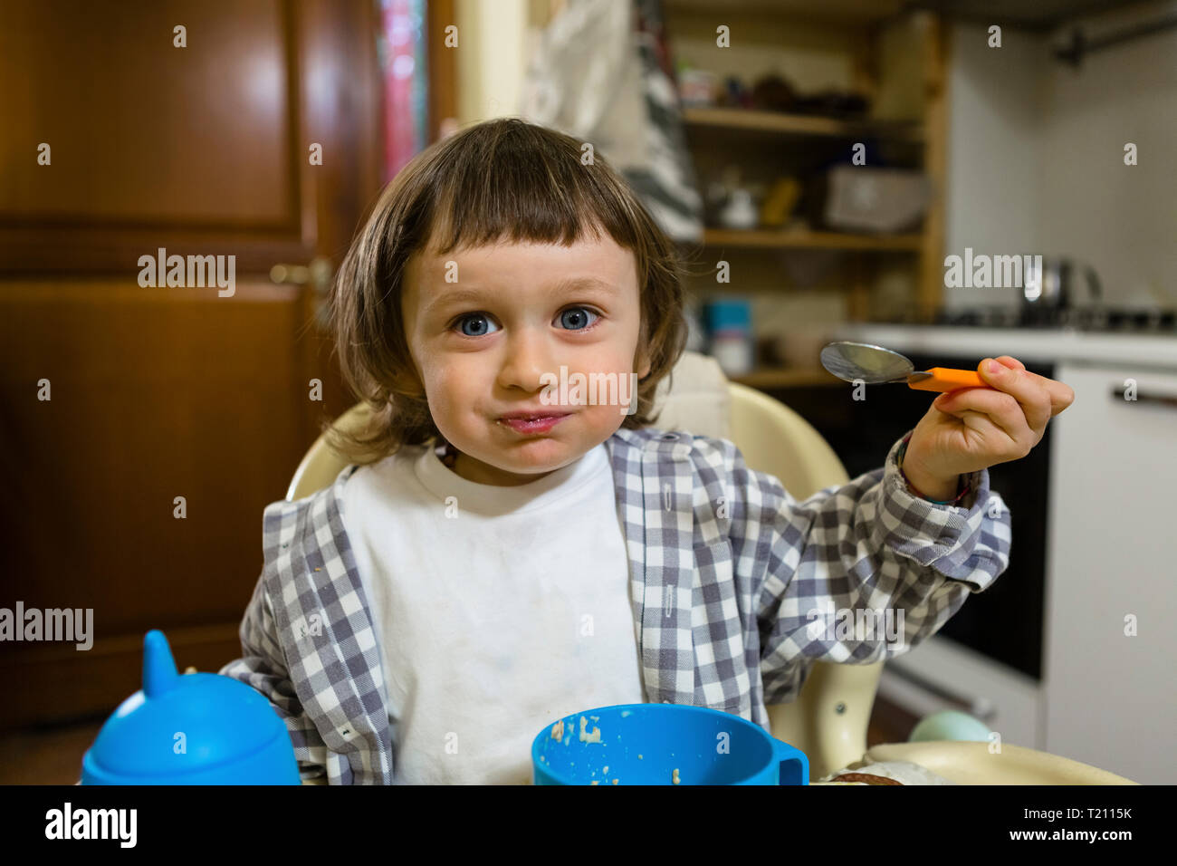 Portrait von süßen Kleinkind Junge sitzt im Hochstuhl in der Küche Stockfoto
