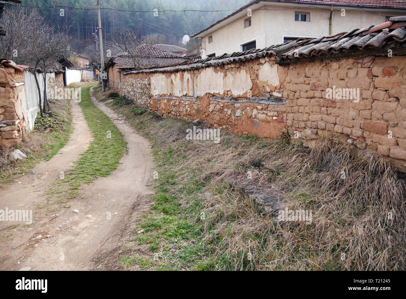 Dirt Road in einem halb verlassenen Dorf. Bulgarien, Osteuropa. Die Menschen bewegen sich zu großen Städten. Die Dörfer sind verlassen, die Häuser sind verlassen und Cr Stockfoto