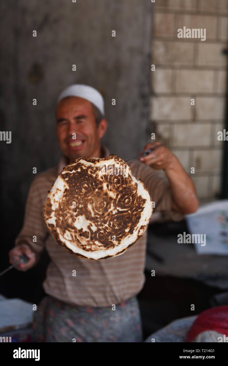 Portrait von Chinesen in Turpan, traditionellen Fladenbrot mit einem Muster auf der Kruste im freien Markt Stockfoto