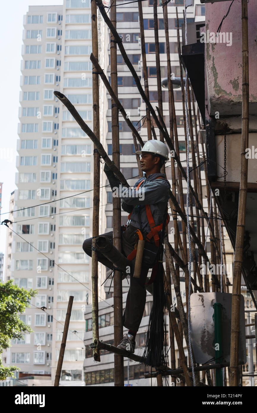 Porträt eines chinesischen Bauarbeiter mit weißen harten Hut stehend auf Bambus Gerüst mit Tools Stockfoto