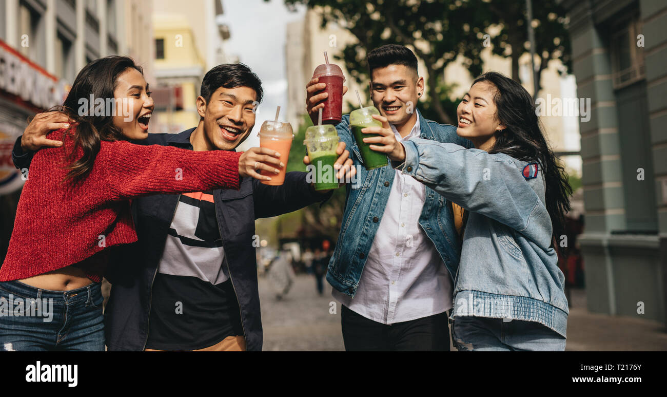 Fröhlicher junger Freunde toasten Getränke auf der Straße. Zwei asiatische paar Getränke genießen im Freien in der Stadt. Stockfoto