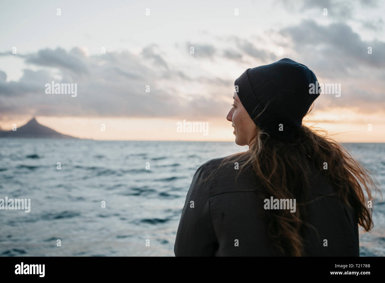 Südafrika, junge Frau mit wollmütze während der Bootsfahrt bei Sonnenuntergang Stockfoto