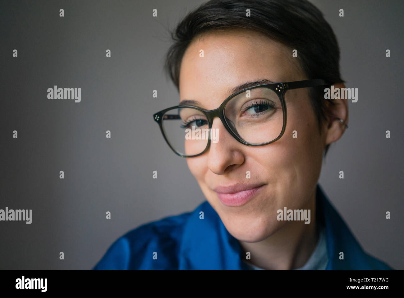 Porträt eines lächelnden jungen Frau mit kurzen Haaren, Brille Stockfoto