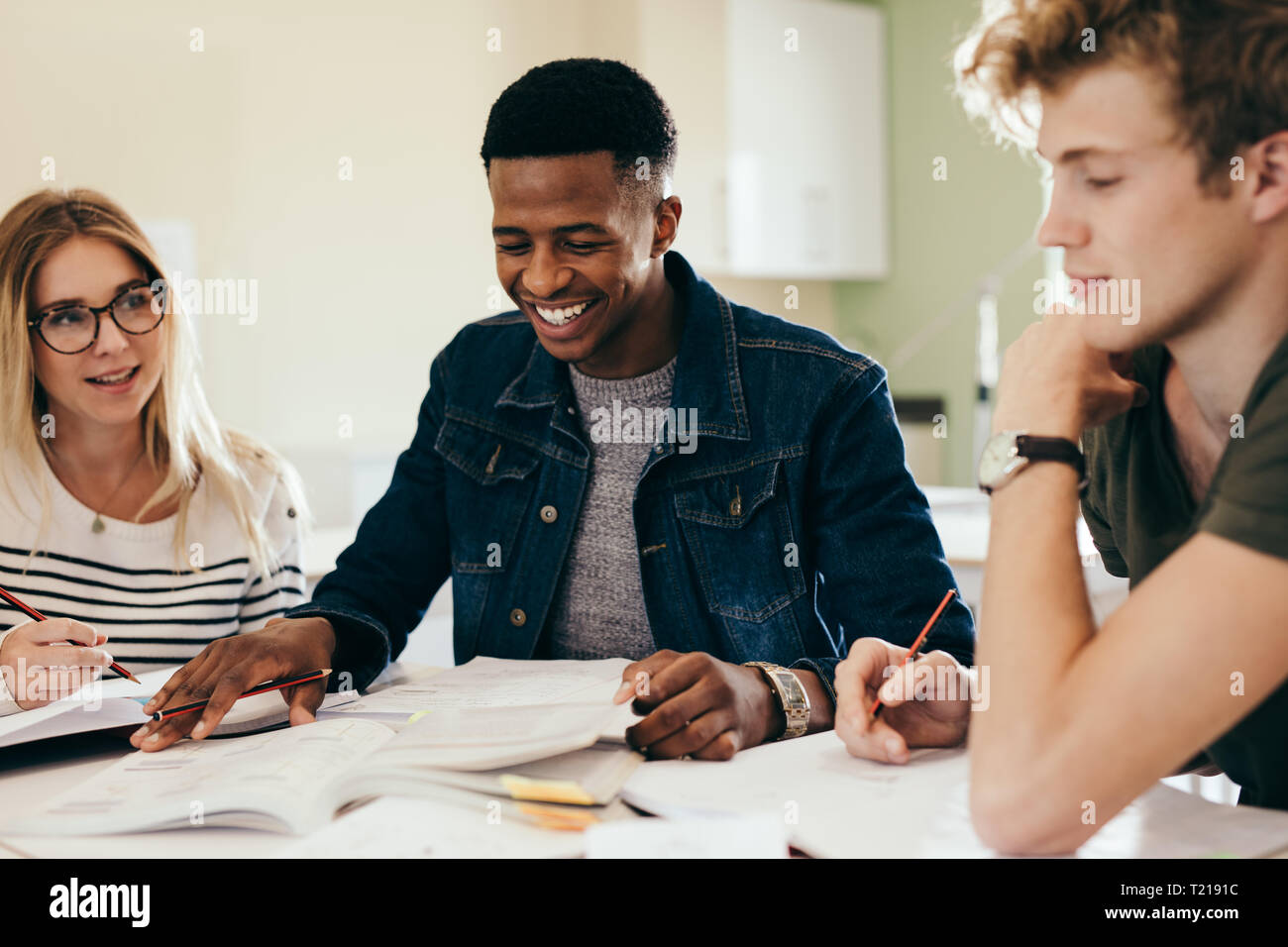 Vielfältige Gruppe von Studenten diskutieren auf Notizen. Glücklich und lächelnd Schüler studieren an der Bibliothek. Stockfoto