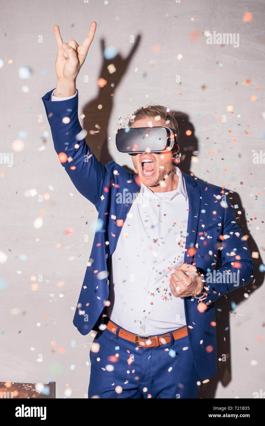 Schreienden jungen Mann Mann mit Virtual Reality Brillen zwischen Konfetti stehend auf einer Party Dusche Stockfoto