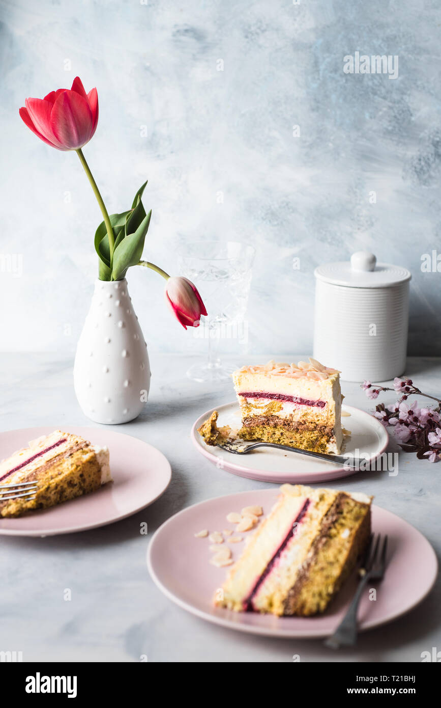 Scheiben von Mousse au chocolat Torte auf einem Teller und einer Tulpe Blumen in einer weißen Vase Stockfoto