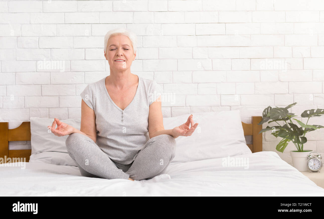 Meditation. Ältere Frau, meditieren, im Bett, im Lotussitz sitzen und Üben von Anti-stress Yoga, freier Speicherplatz Stockfoto
