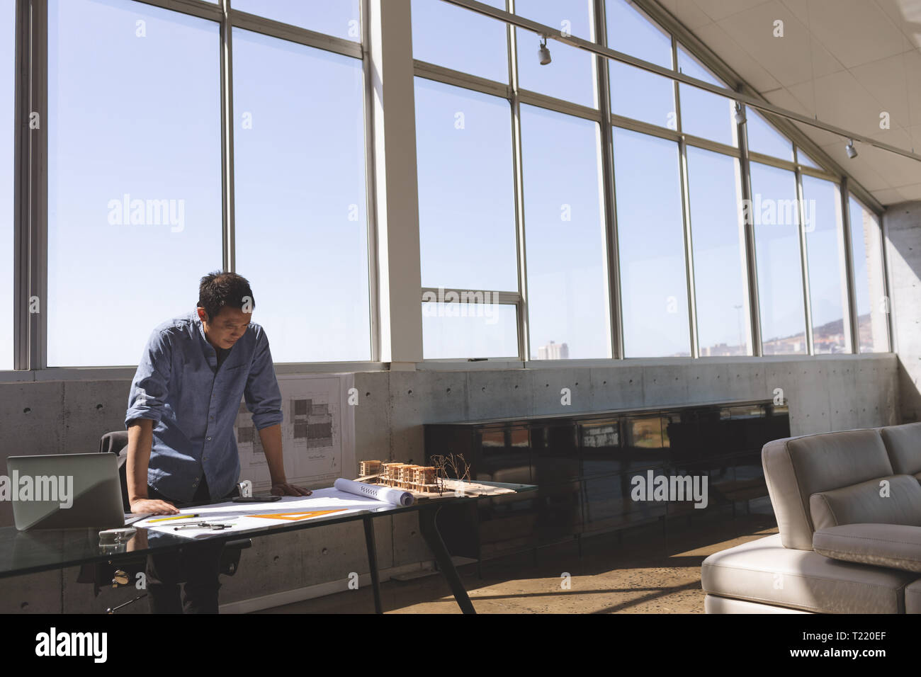 Männliche Architekt am Schreibtisch und suchen Blueprint in einem modernen Büro Stockfoto