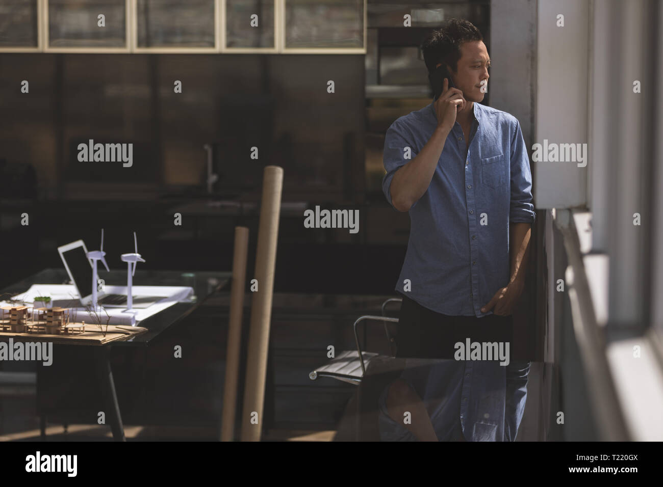 Männliche Architekt Gespräch am Handy beim Stehen in der Nähe der Fenster in einem modernen Büro Stockfoto