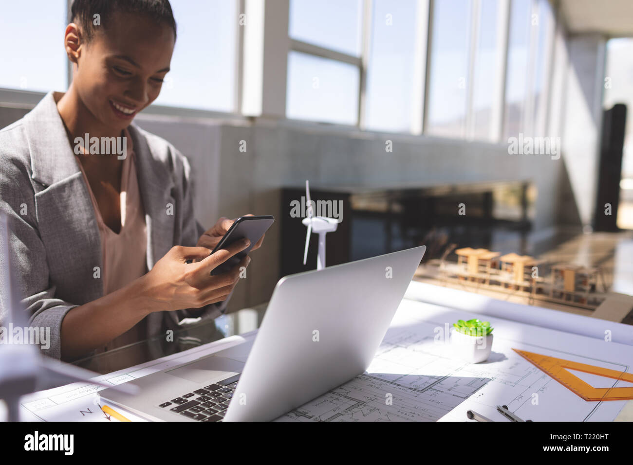 Geschäftsfrau Gespräch am Handy während auf Laptop am Schreibtisch arbeiten Stockfoto