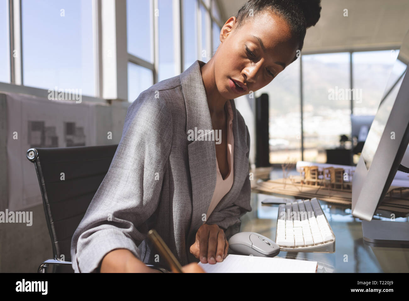 Geschäftsfrau schriftlich auf einem Notizblock Arbeiten am Computer am Schreibtisch Stockfoto