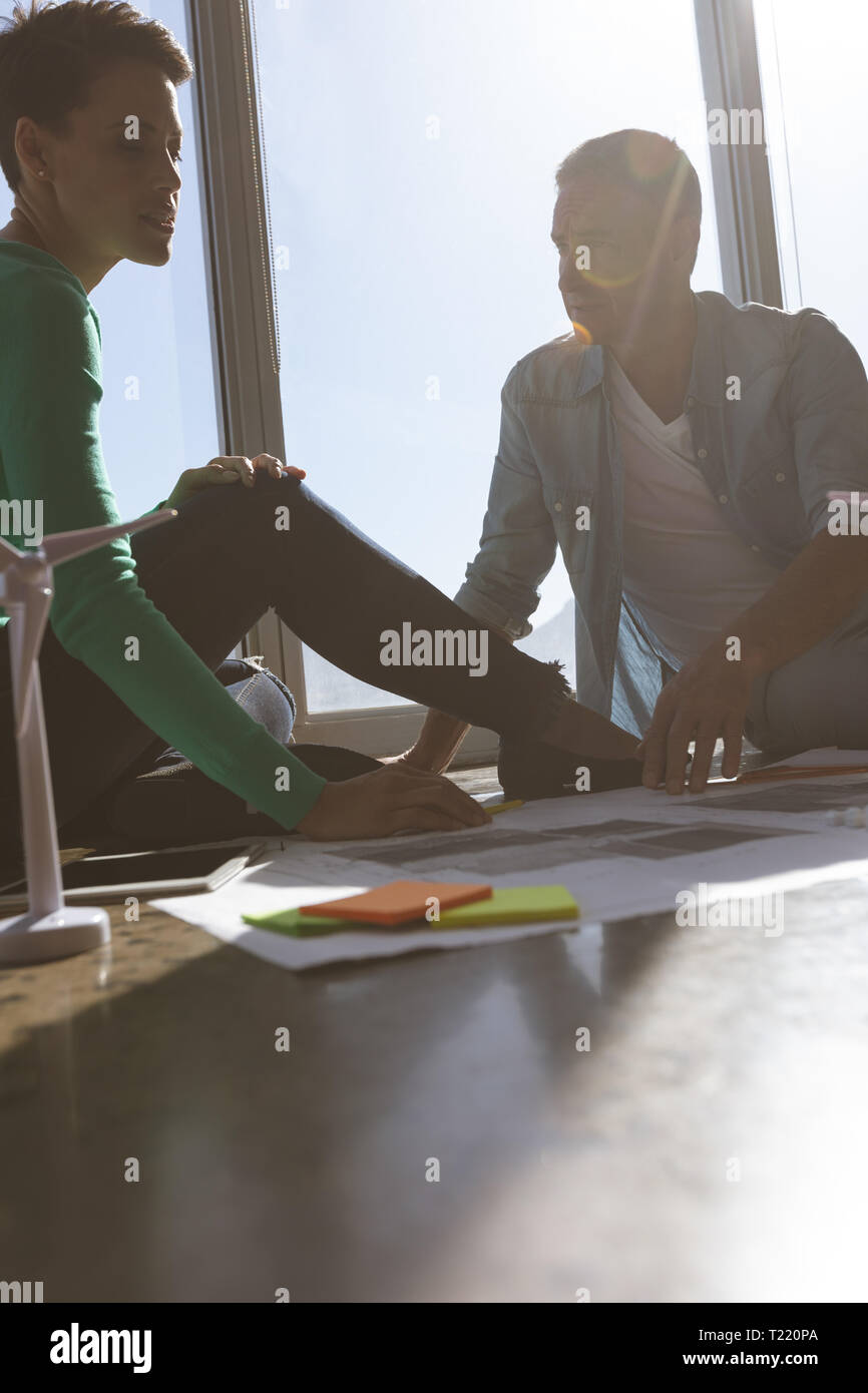 Architekten sitzen auf dem Boden und Diskutieren über Blueprint im Büro Stockfoto