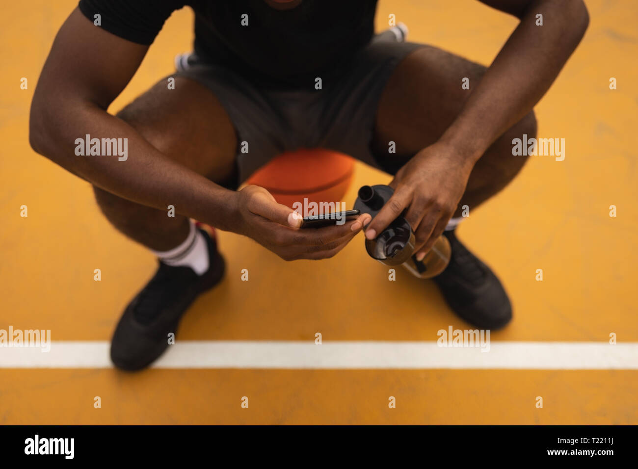 Zuversichtlich player Relaxen im Basketball bei der Verwendung von Mobile phone Stockfoto